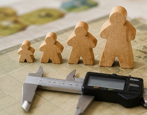 Wooden meeple size comparison with caliper showing different heights for custom board game pieces
